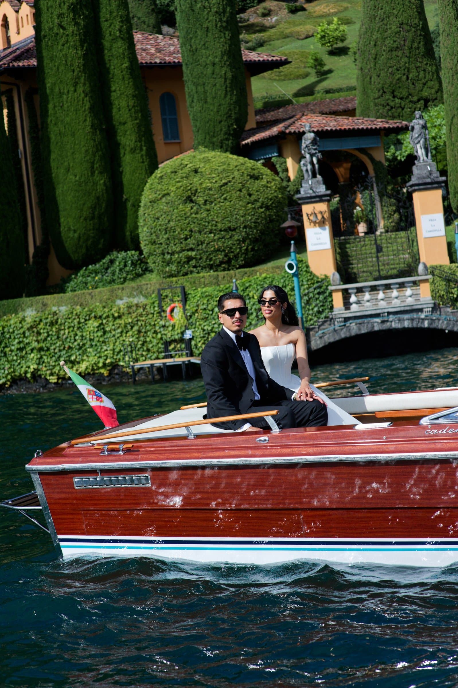 The bride and groom in a varnished Riva at a villa landing on Lake Como
