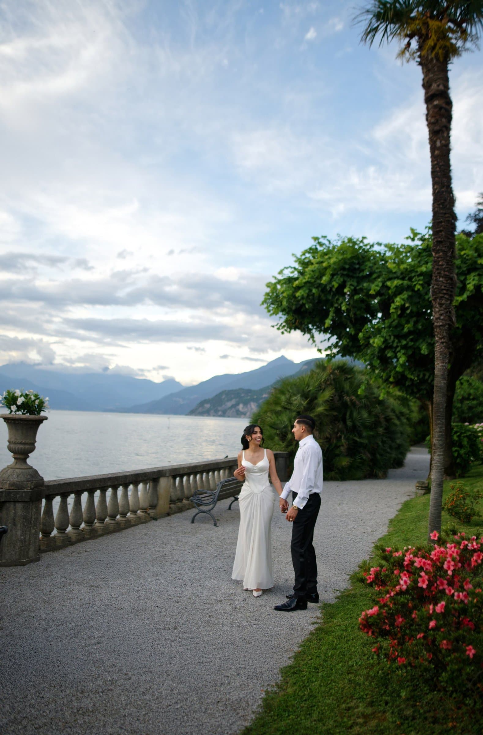 The couple on a lakeside promenade under palms in the evening