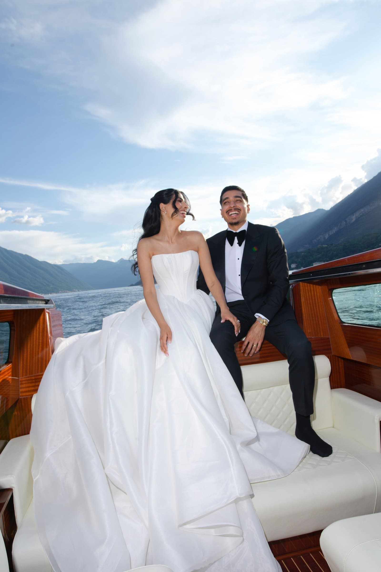 The bride and groom aboard a wooden boat on Lake Como, the groom in a black tuxedo