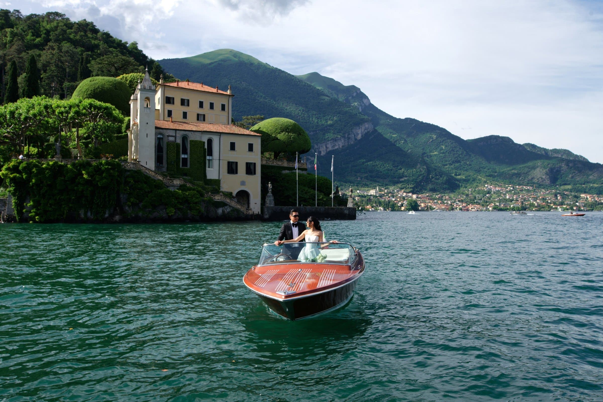 A wooden Riva carrying the couple past a villa on Lake Como