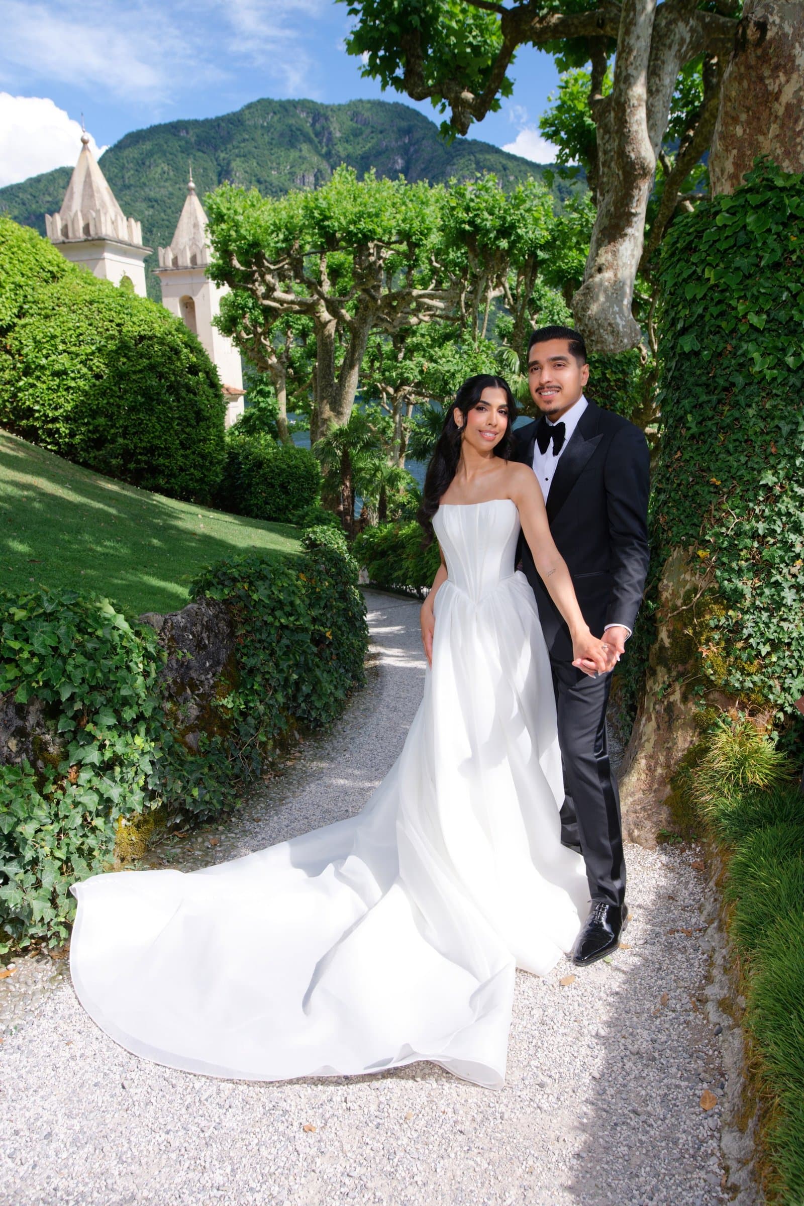 The bride and groom on a garden path between clipped hedges