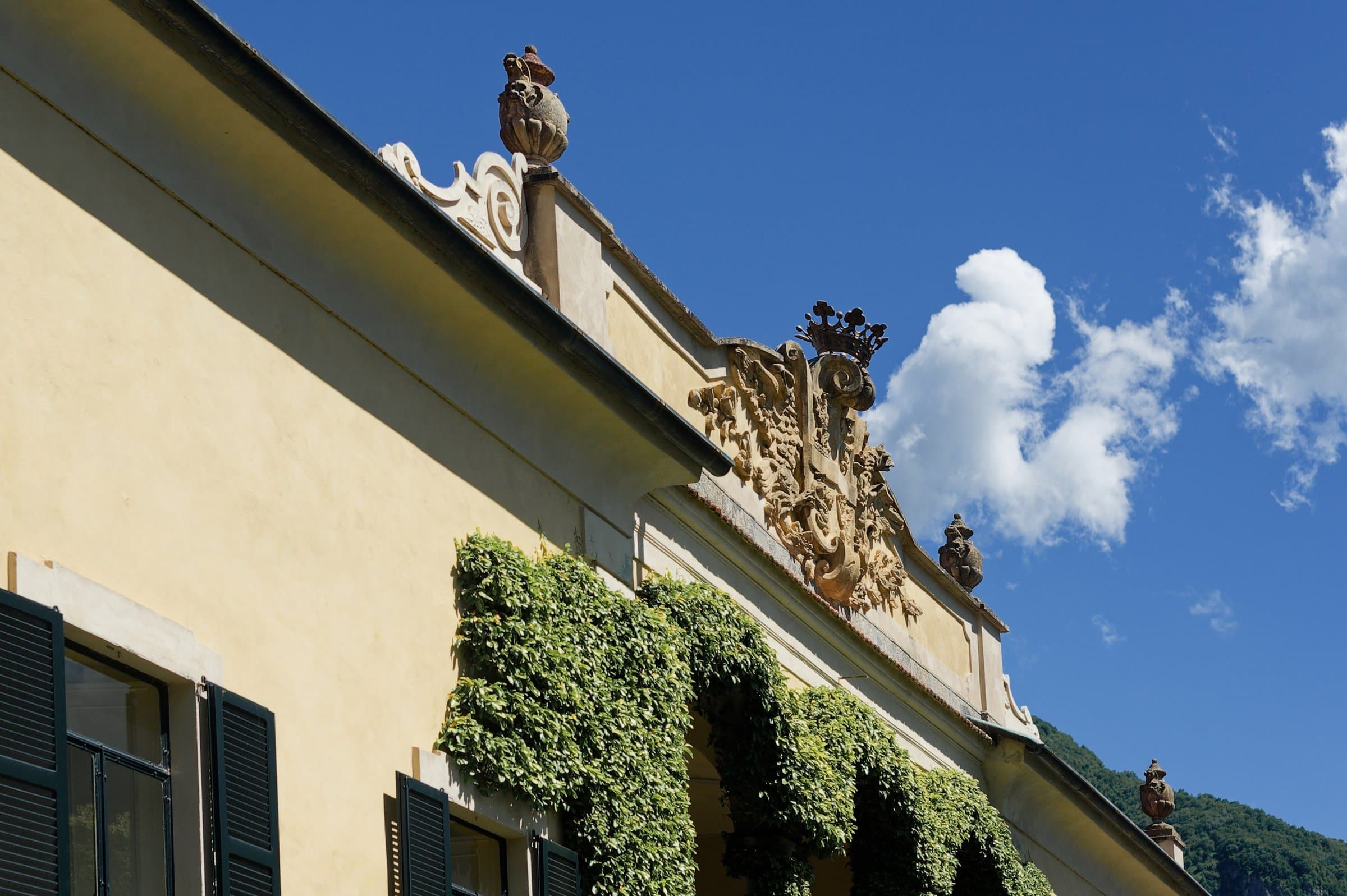Ivy and baroque stonework on a villa facade under a blue sky