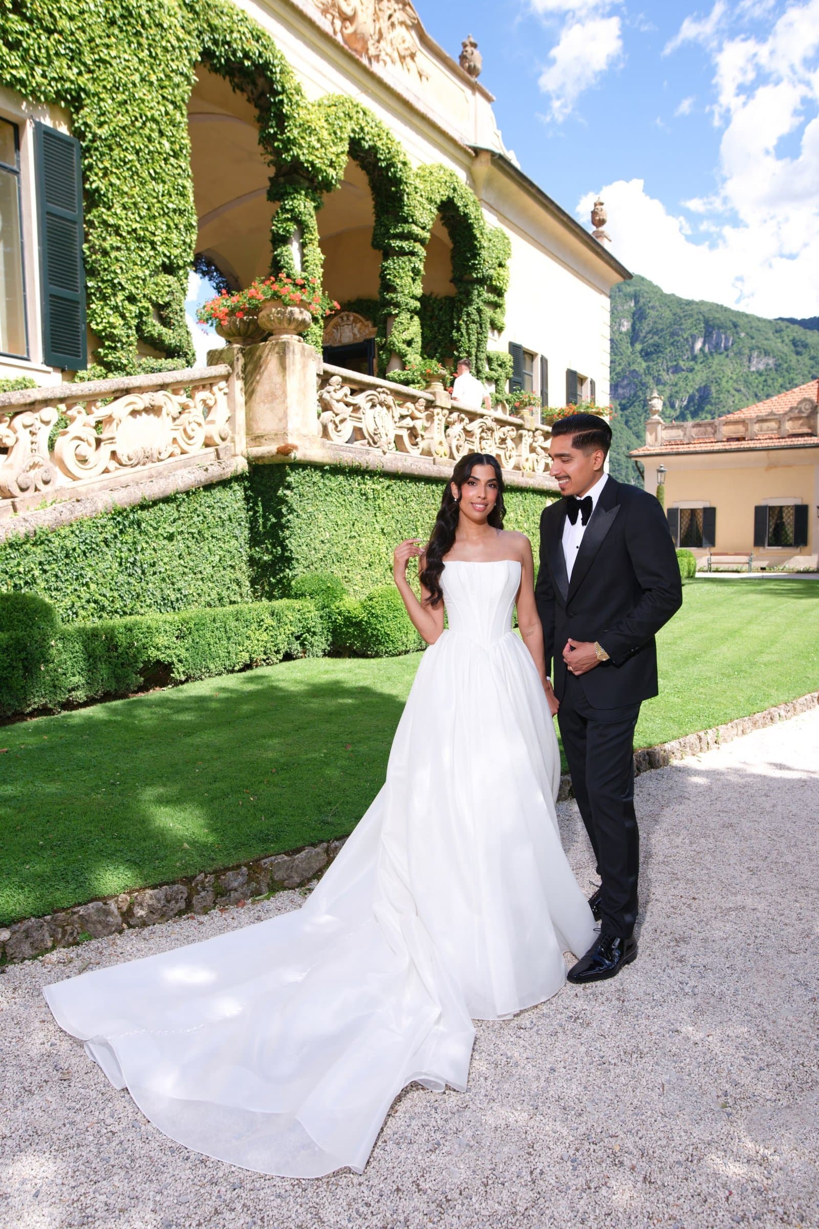 The bride and groom on the villa lawn below an ivy-covered loggia