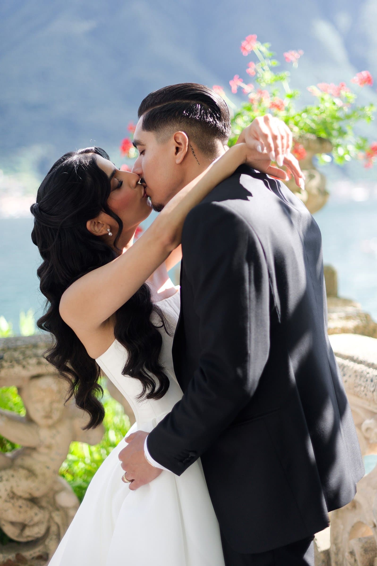 The bride and groom kissing on a villa terrace, the groom in a black tuxedo
