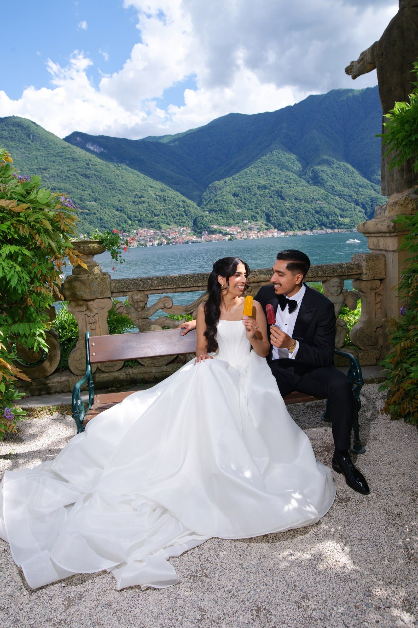 The bride and groom laughing together on a garden bench above Lake Como