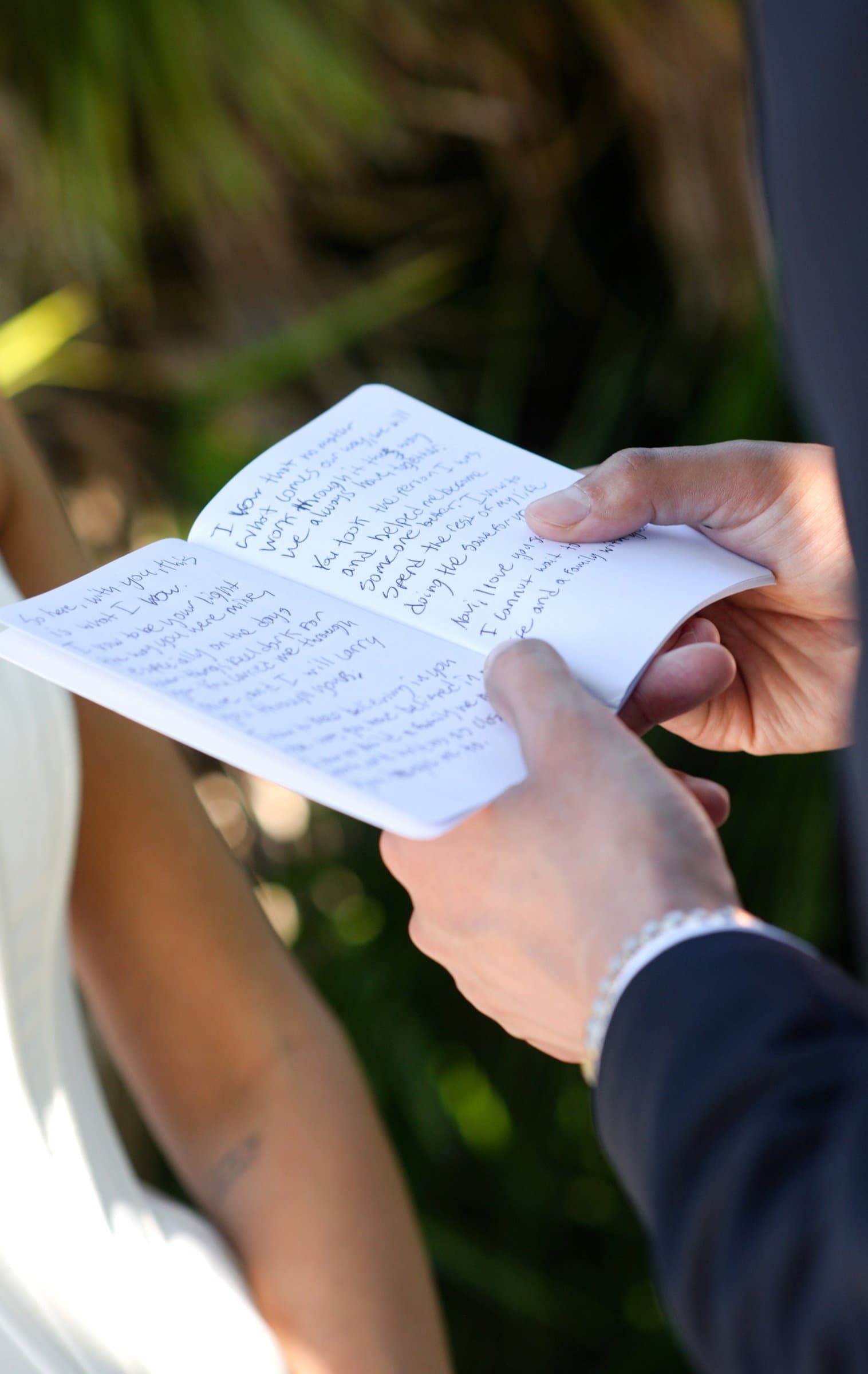 The groom's hands holding his handwritten vows