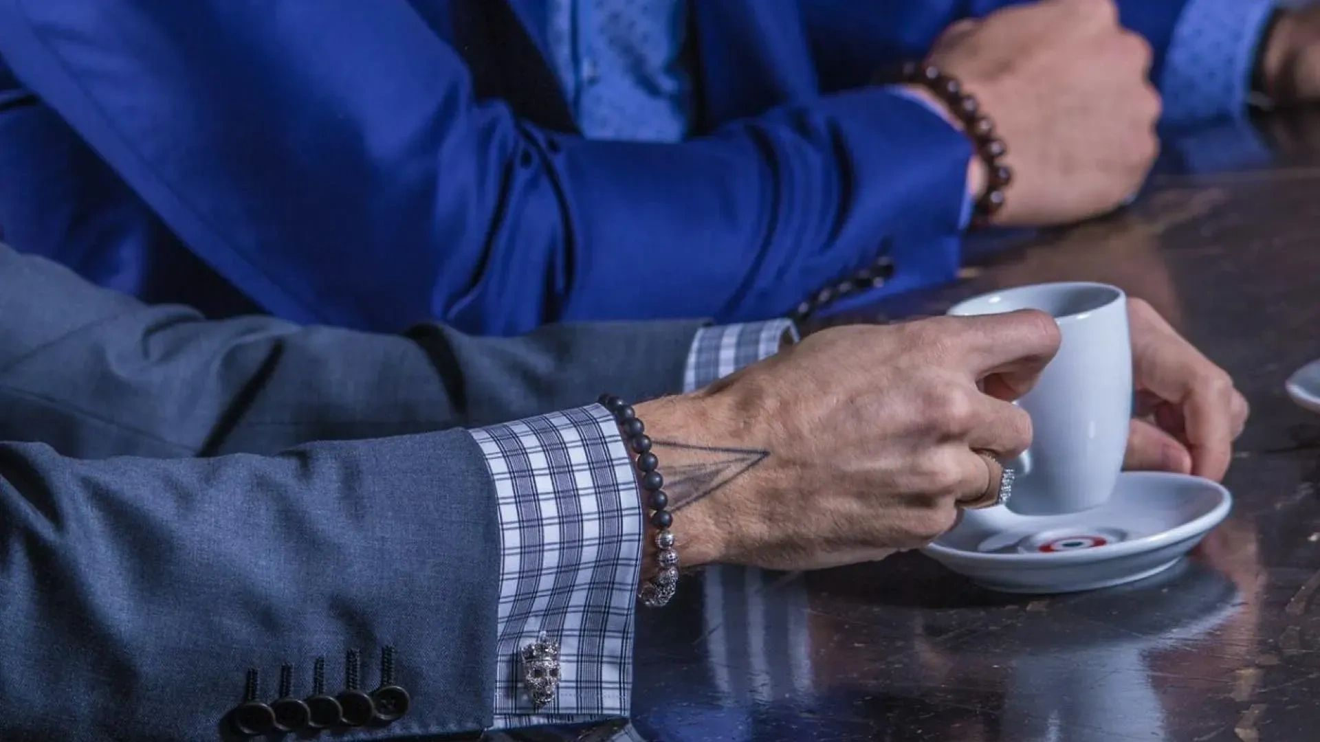 Blue business suit jacket and checked shirt cuff beside a coffee cup, tailored in Edmonton