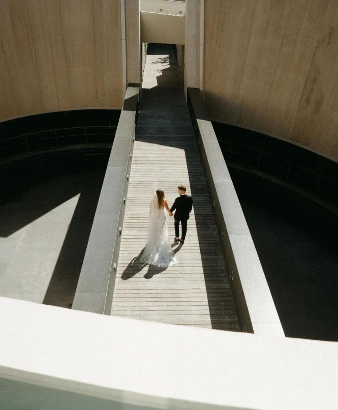 Bride and groom on a geometric outdoor staircase, wedding tailoring from Edmonton