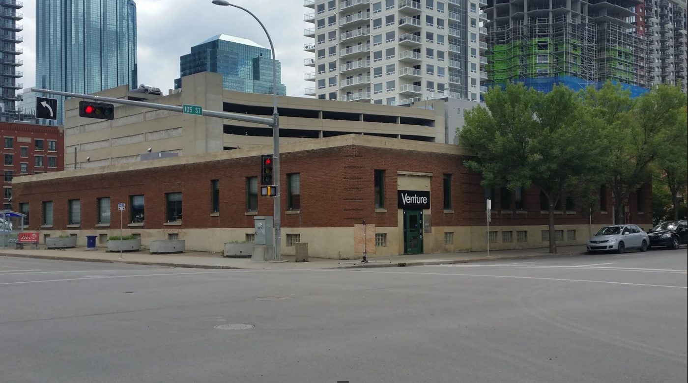 The Conxeppt building on 105 Street: a long red brick wall with a green door under a black sign