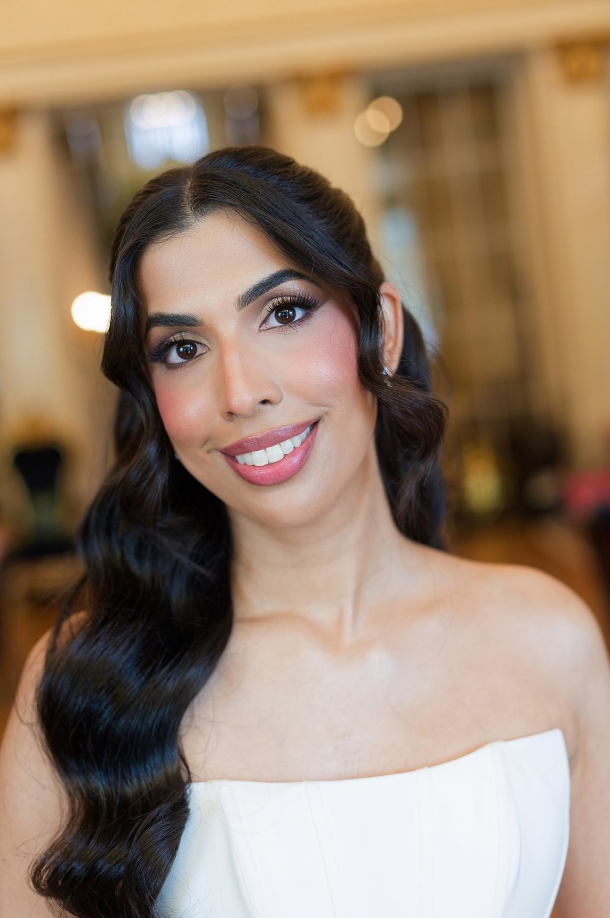 The bride smiling before the ceremony, in a strapless ivory gown