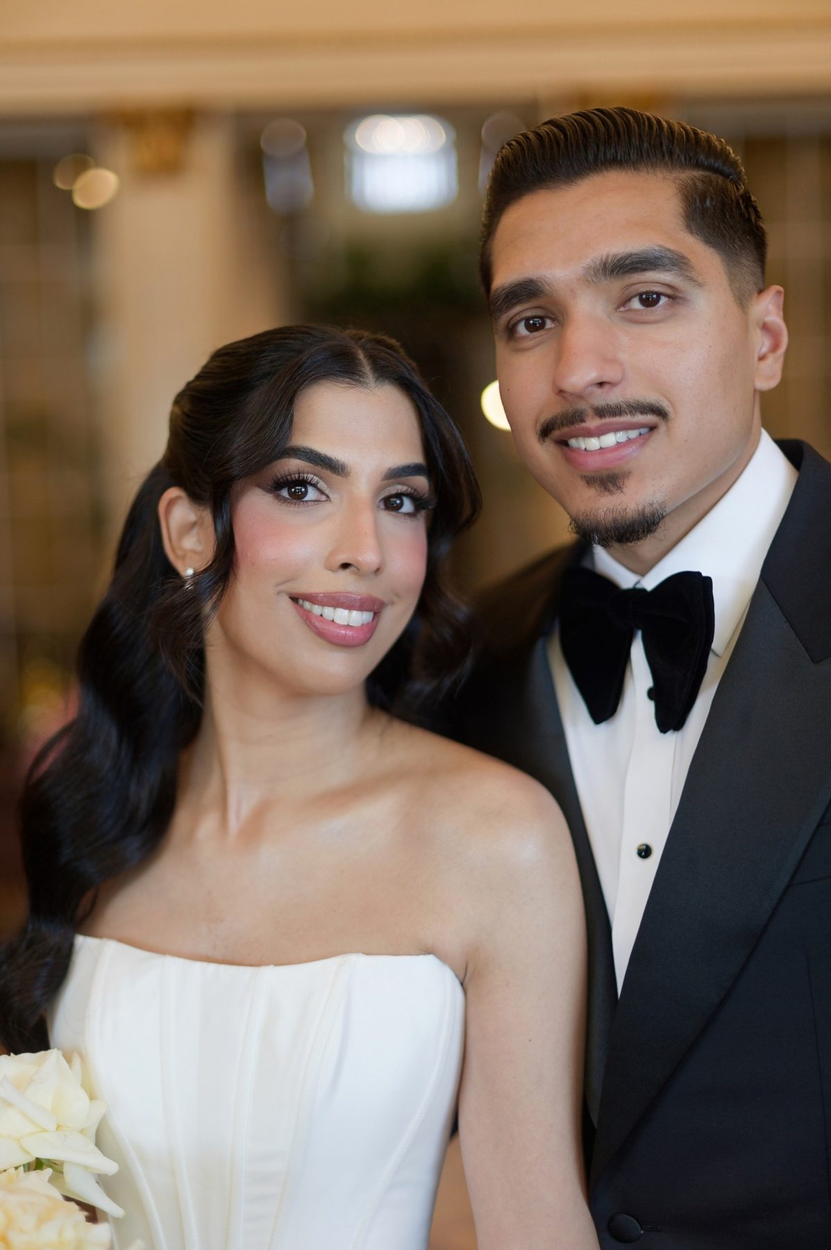The bride and groom close together, black tie against ivory