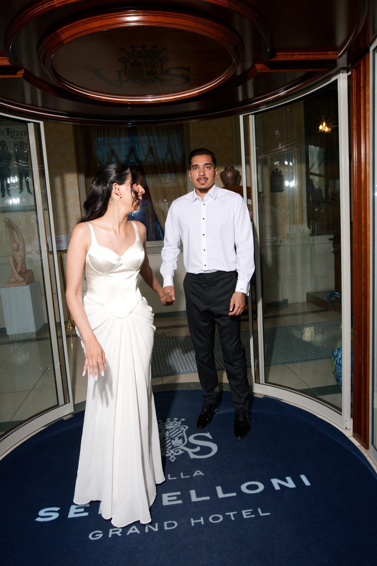 The couple dressed for the evening in white at the doors of the Grand Hotel Villa Serbelloni