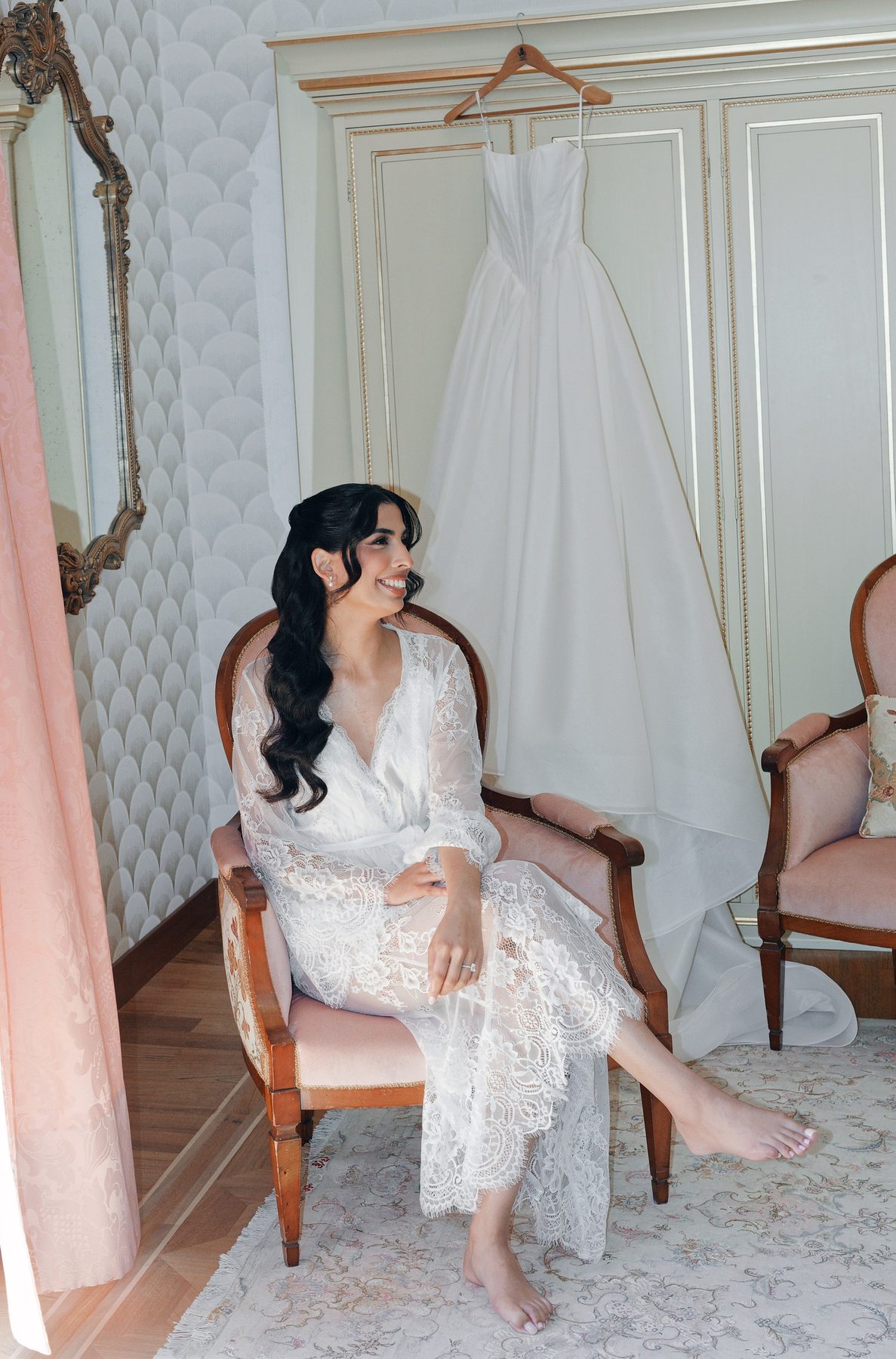 The bride getting ready in the villa, her gown hanging behind her