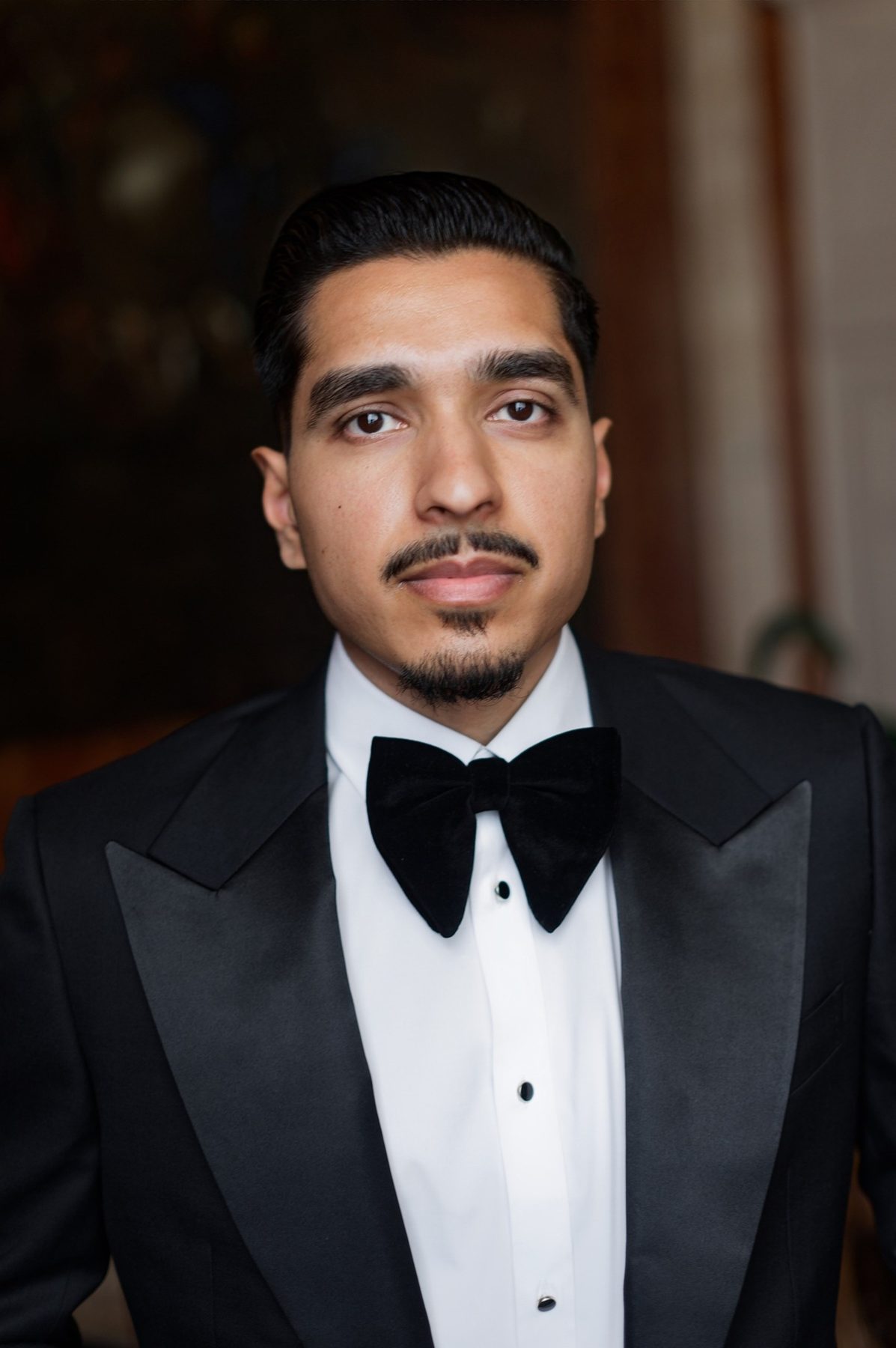 The groom in a Conxeppt custom black tuxedo with a satin peak lapel