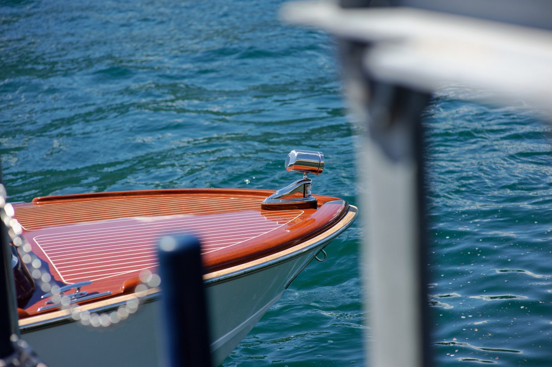 The varnished bow of a wooden Riva on the lake