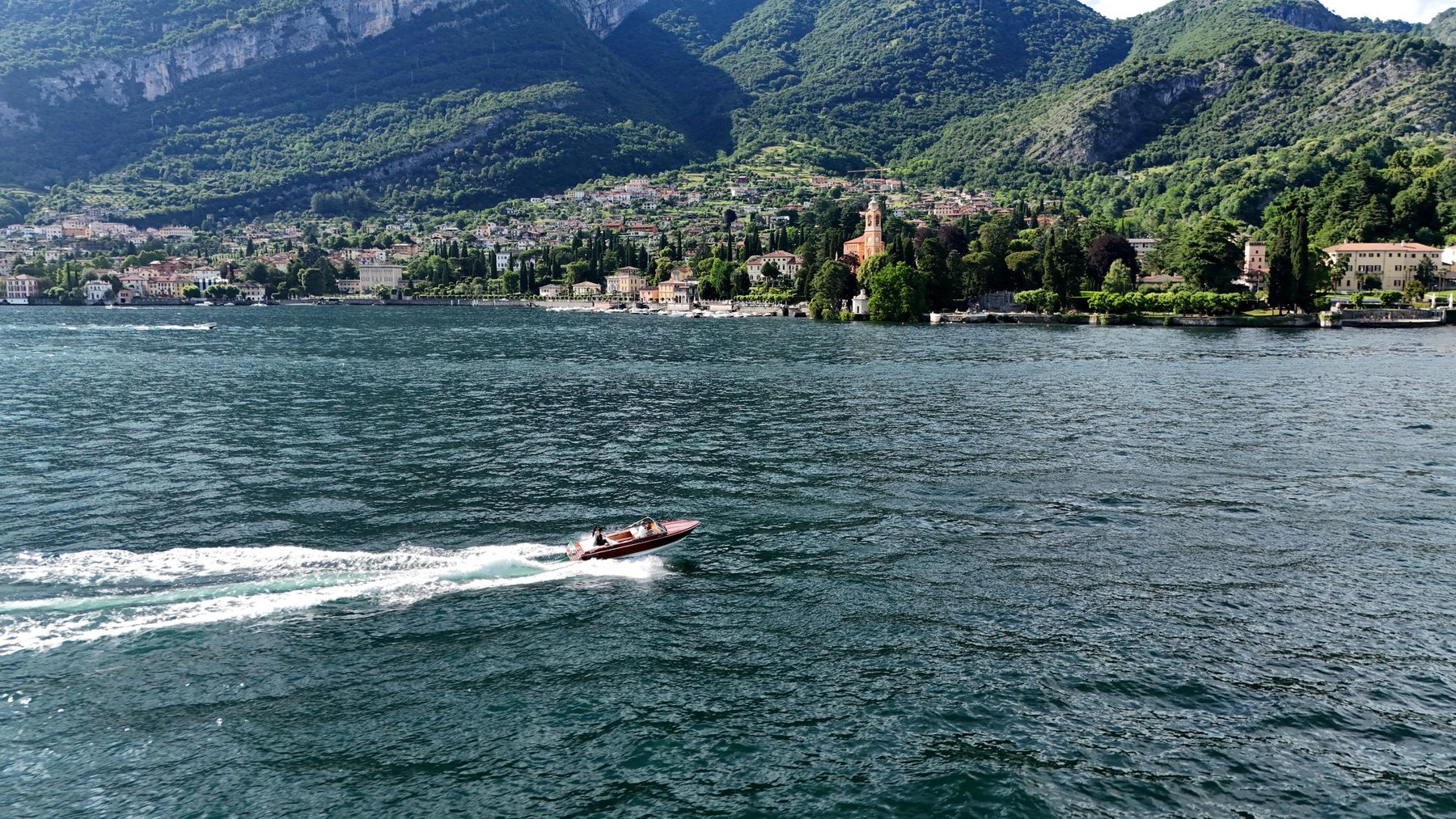 A speedboat drawing a long wake across Lake Como