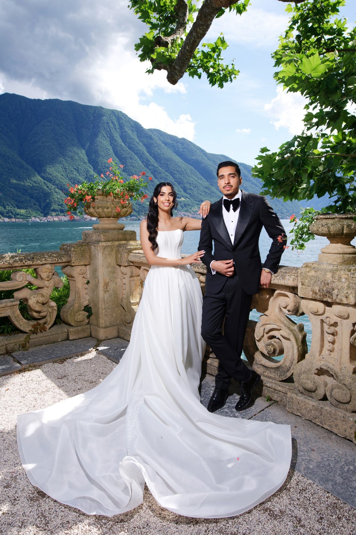 The bride and groom at a carved balustrade above the lake, the groom in a black tuxedo