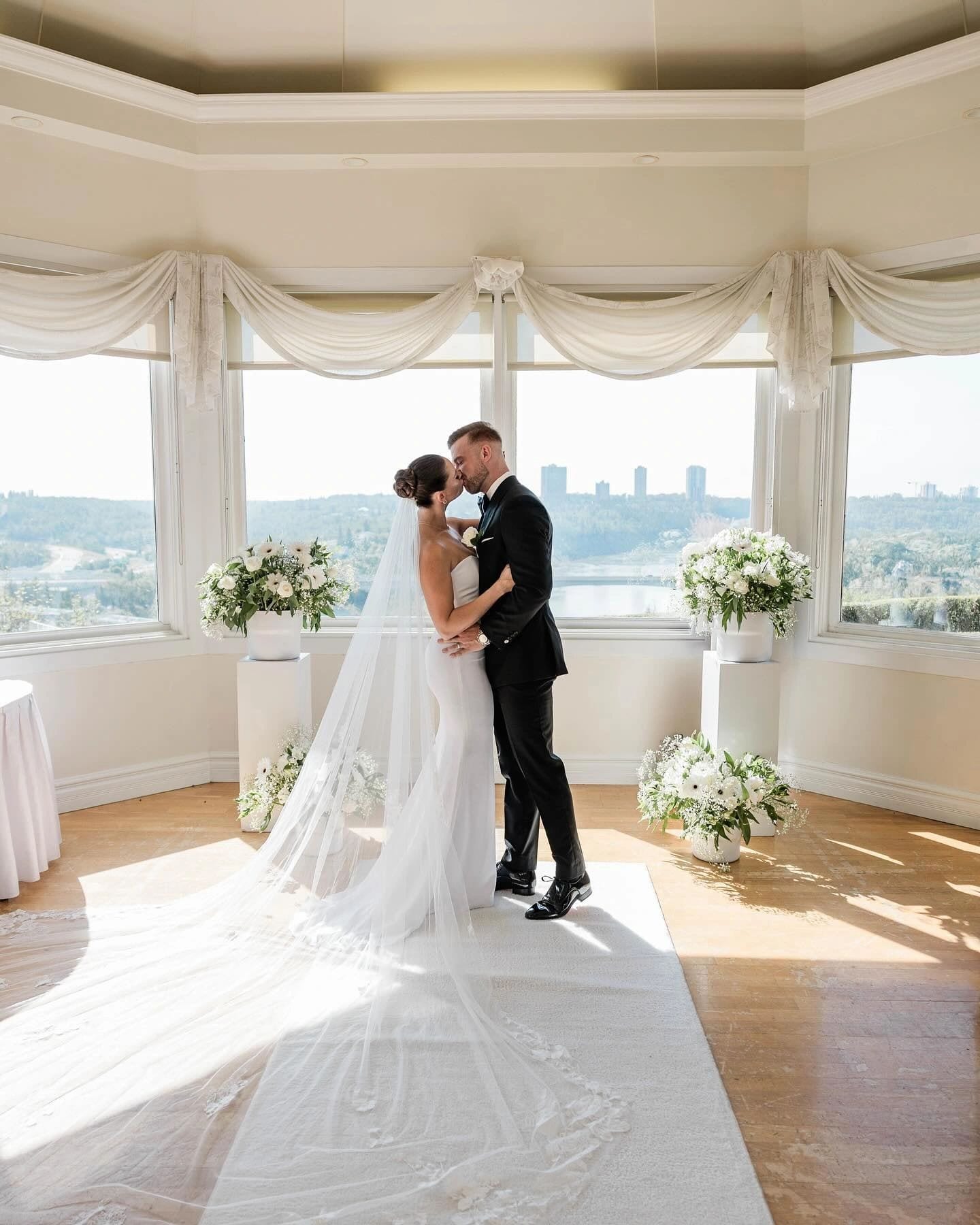 Couple kissing beneath a gazebo overlooking a valley, wedding tailoring from Edmonton