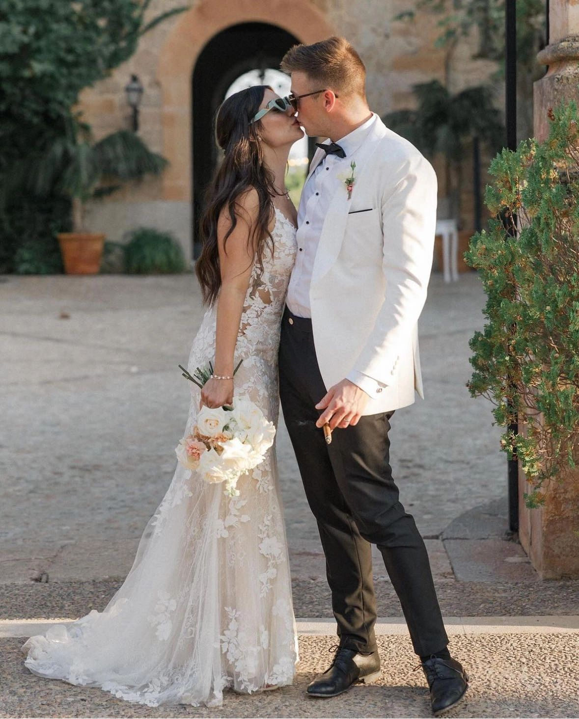 Couple standing in a garden, the groom in a white wedding jacket and bow tie, tailored in Edmonton